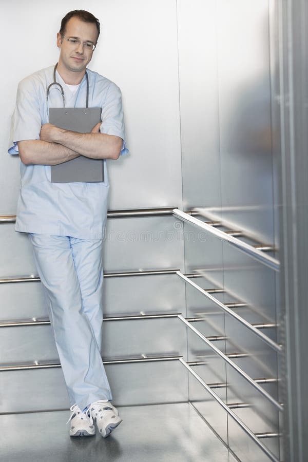 Full length of a male physician waiting in the elevator. Standing file folder stock images, royalty-free photos and pictures