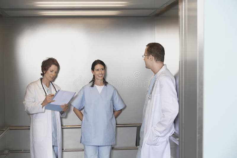 Male and female physicians talking in elevator talking. Standing file folder stock images, royalty-free photos and pictures