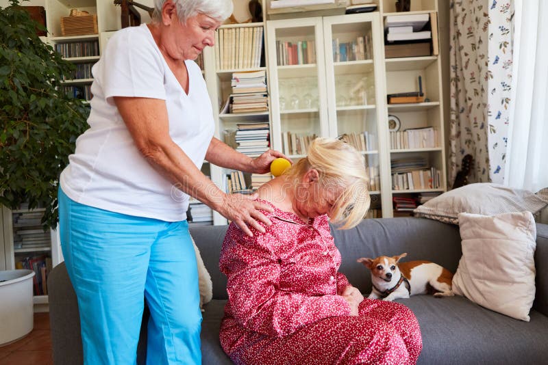 Physiotherapist gives senior citizens a neck massage with a massage ball against tension. Physiotherapist gives senior citizens a neck massage with a massage ball against tension