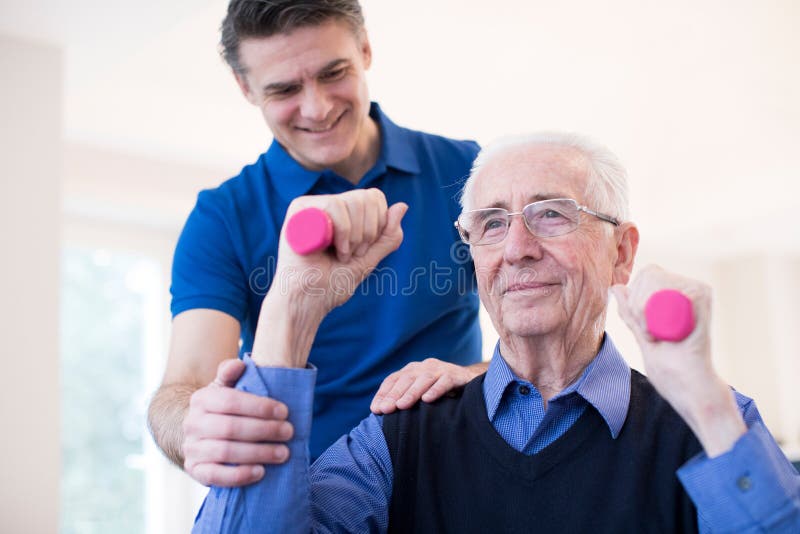 Physiotherapist Pomaga Starszego mężczyzna Podnosić ręka ciężary zdjęcie royalty free Physiotherapist Pomaga Starszego mężczyzna Podnosić ręka ciężary zdjęcie royalty free