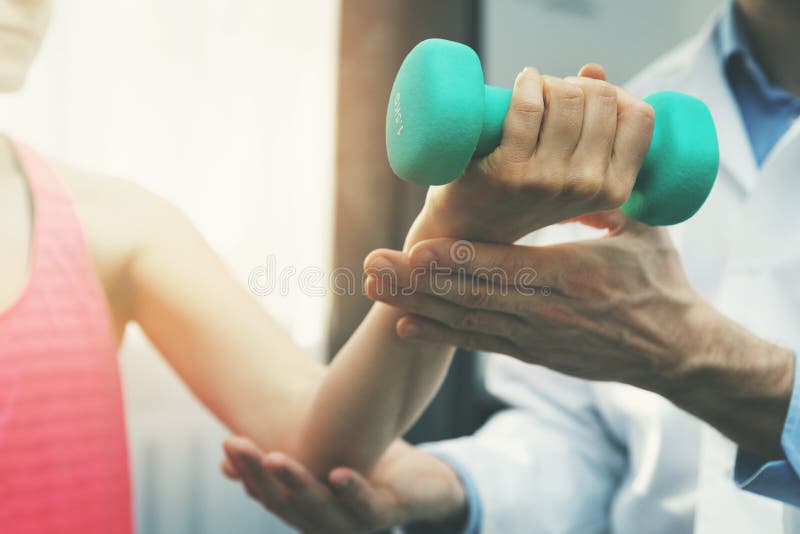 physiotherapy - physiotherapist help woman patient to recover from hand injury. dumbbell exercises