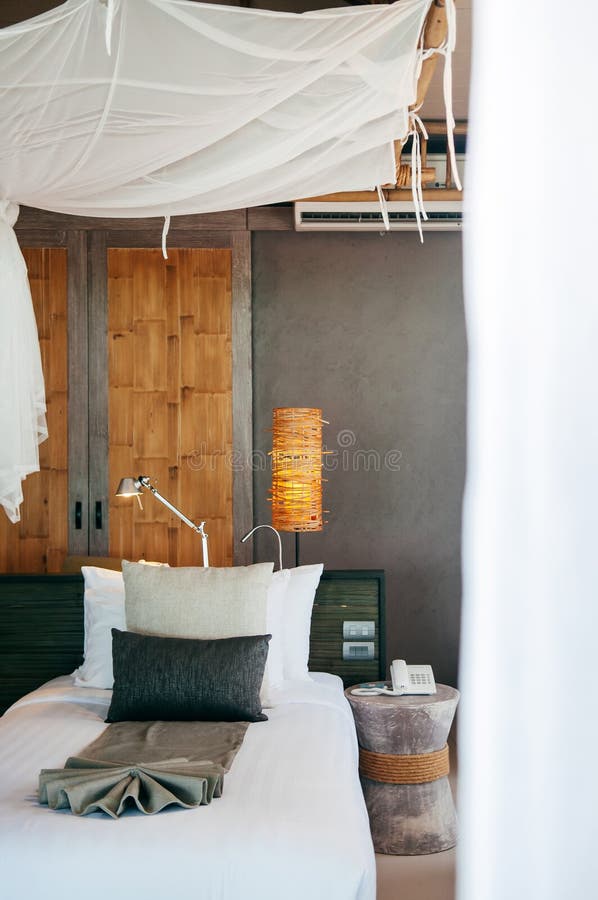 Pi?ce tropicale tha?landaise asiatique de lieu de vill?giature luxueux avec le lit en bois et le rideau blanc photographie stock libre de droits Pi?ce tropicale tha?landaise asiatique de lieu de vill?giature luxueux avec le lit en bois et le rideau blanc photographie stock libre de droits