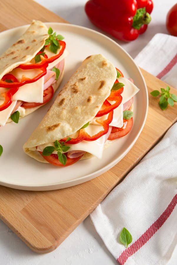 Piadina romagnola - Ιταλικό ψωμί με προσούτο, ντομάτα, βασιλικό, πιπέρι και τυρί σε λευκό φόντο Κλείσιμο στοκ εικόνες Piadina romagnola - Ιταλικό ψωμί με προσούτο, ντομάτα, βασιλικό, πιπέρι και τυρί σε λευκό φόντο Κλείσιμο στοκ εικόνες