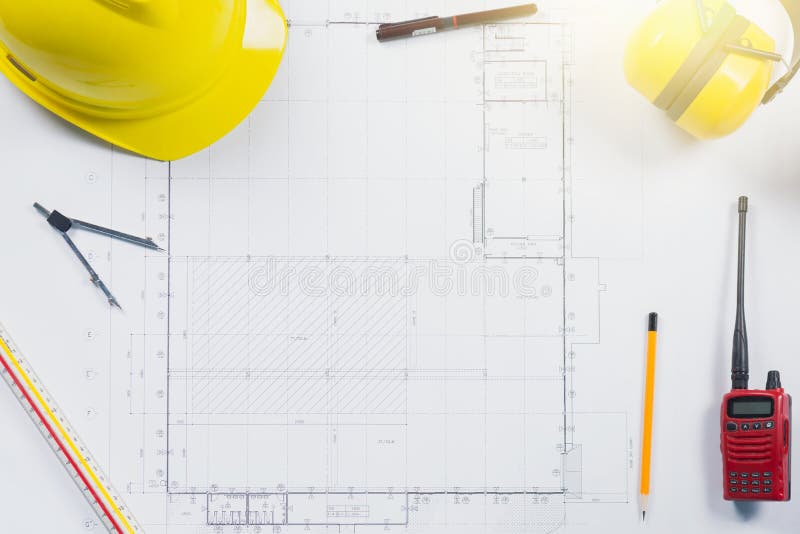 Piani della costruzione con il casco ed il disegno gialli fotografia stock Piani della costruzione con il casco ed il disegno gialli fotografia stock