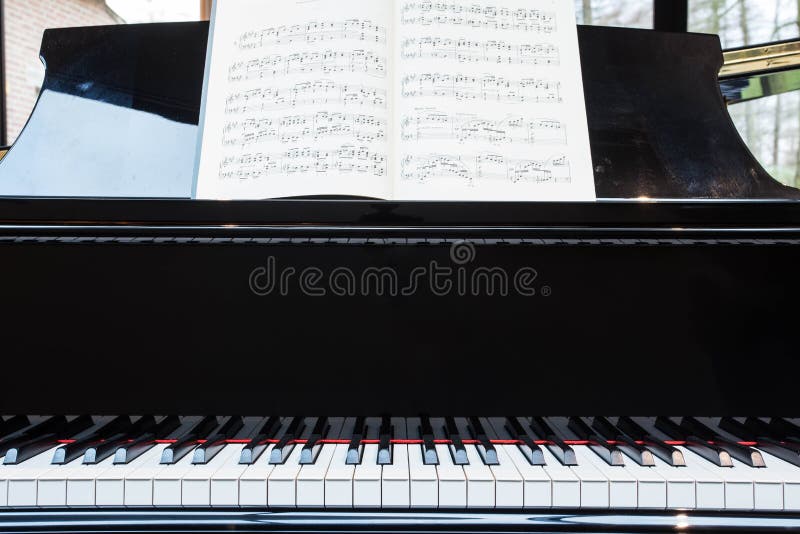 Piano clássico preto com livro de música imagem de stock Piano clássico preto com livro de música imagem de stock