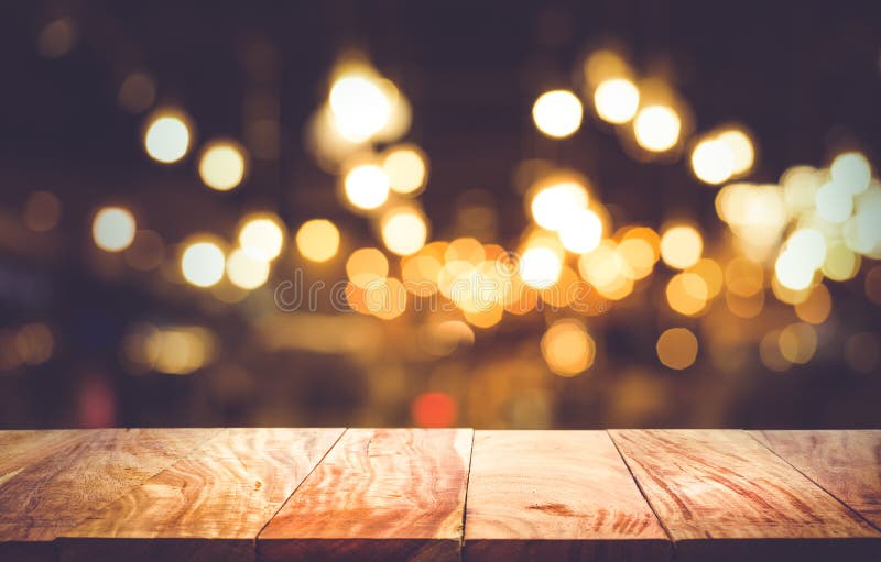 Piano d'appoggio di legno vuoto sul bokeh della luce della sfuocatura nel resto scuro del caffè di notte fotografie stock libere da diritti Piano d'appoggio di legno vuoto sul bokeh della luce della sfuocatura nel resto scuro del caffè di notte fotografie stock libere da diritti