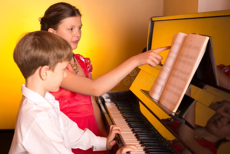 Sister play piano. Мальчик и девочка играют на пианино. Мальчик за фортепьяно. Мальчик и девочка на фортепиано. Мальчик за пианино.