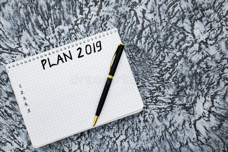 Piano per 2019, blocco note e penna su un fondo grigio strutturato immagine stock Piano per 2019, blocco note e penna su un fondo grigio strutturato immagine stock