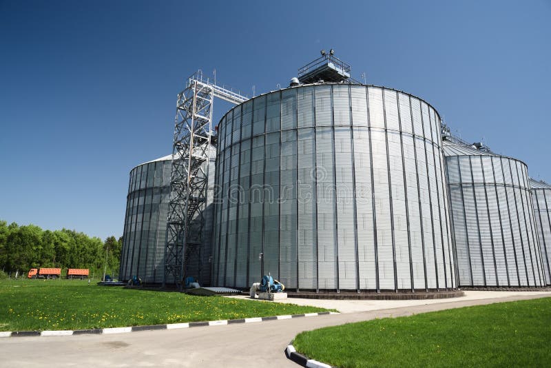 Pianta moderna per stoccaggio ed i raccolti di elaborazione Paesaggio industriale Grandi granai nel giorno di estate soleggiato fotografie stock libere da diritti Pianta moderna per stoccaggio ed i raccolti di elaborazione Paesaggio industriale Grandi granai nel giorno di estate soleggiato fotografie stock libere da diritti