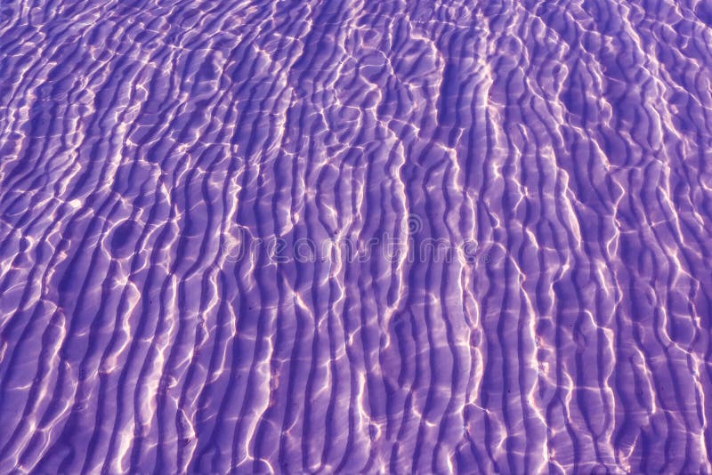 Piasek i morze z odbijamy światło słoneczne purpur tło