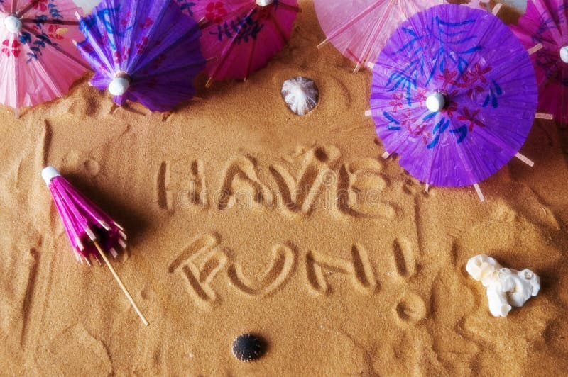 Have fun! written on sand with colorful umbrellas and seashells. Soft focus for dreamy atmosphere. Have fun! written on sand with colorful umbrellas and seashells. Soft focus for dreamy atmosphere.