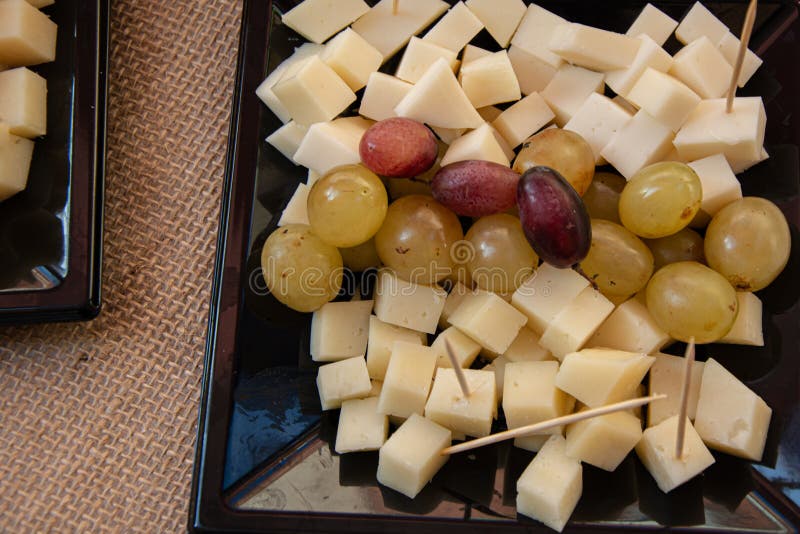 Piastra con formaggi e uva diversi in primo piano su fondo di sughero immagini stock libere da diritti
