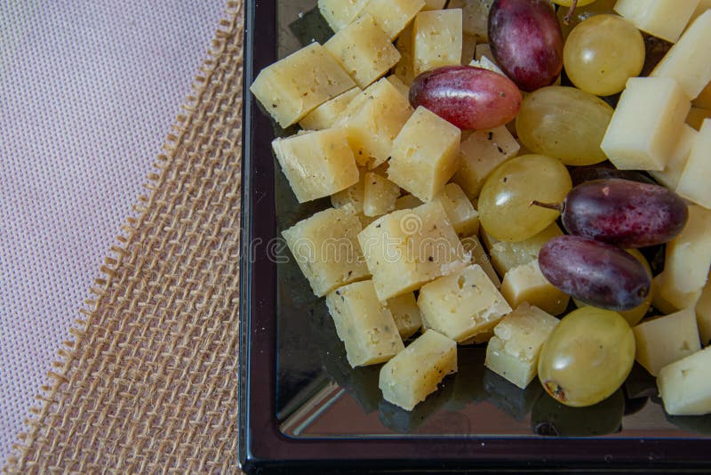 Piastra con formaggi e uva diversi in primo piano su fondo di sughero fotografie stock libere da diritti
