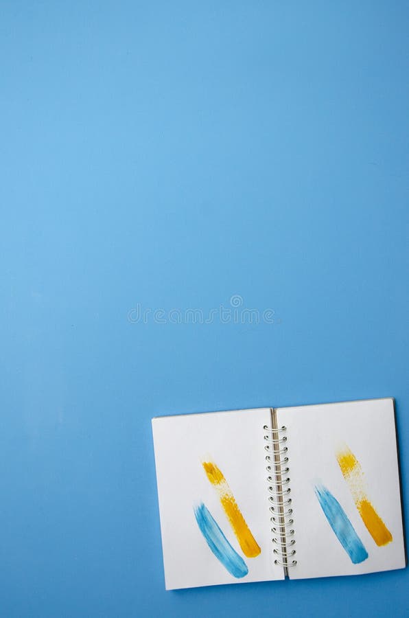Piastra di fissaggio composizione verticale blocco appunti aperto con tratti gialli e blu di pittura su pagine bianche pulsanti a fotografia stock