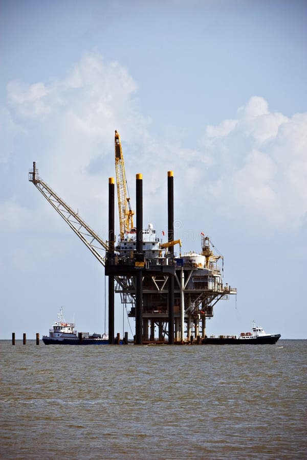 Oil drilling platform in the ocean with two boats underneath. Oil drilling platform in the ocean with two boats underneath.