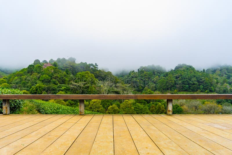 Piattaforma di legno davanti al hil del paesaggio dell'azienda agricola di platation del tè verde immagine stock libera da diritti Piattaforma di legno davanti al hil del paesaggio dell'azienda agricola di platation del tè verde immagine stock libera da diritti