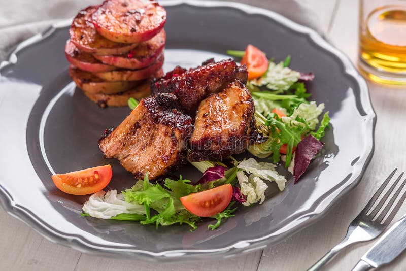 Piatti caldi della carne Le costole di carne di maiale hanno grigliato con insalata e le mele su un piatto fotografie stock libere da diritti Piatti caldi della carne Le costole di carne di maiale hanno grigliato con insalata e le mele su un piatto fotografie stock libere da diritti