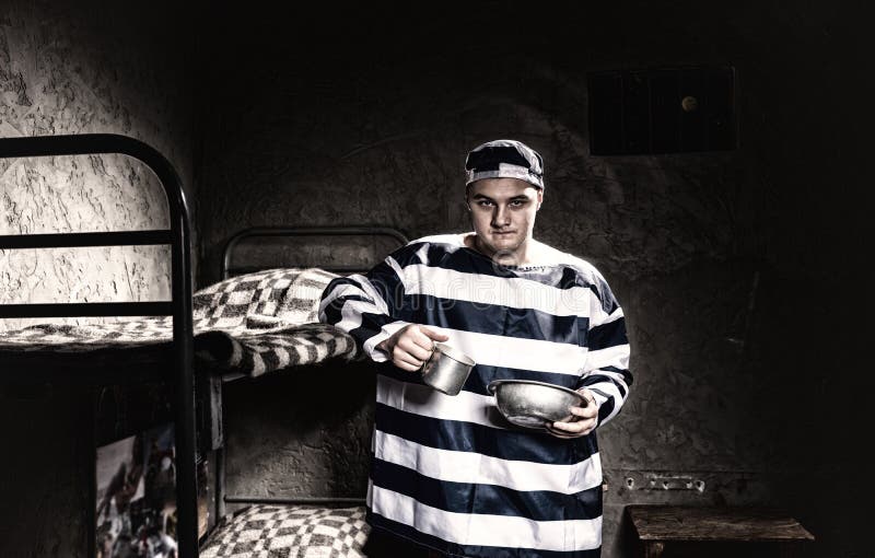 Piatti di alluminio d'uso della tenuta uniforme della prigione del prigioniero arrabbiato dentro fotografia stock Piatti di alluminio d'uso della tenuta uniforme della prigione del prigioniero arrabbiato dentro fotografia stock