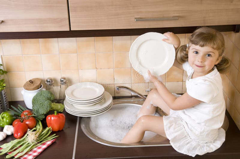 Little girl washing dishes in the kitchen. Little girl washing dishes in the kitchen