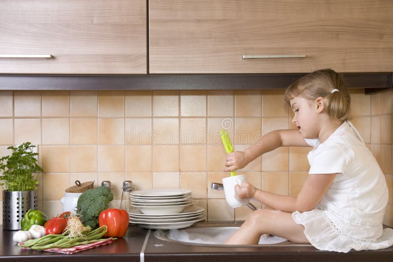 Little girl washing dishes in the kitchen. Little girl washing dishes in the kitchen