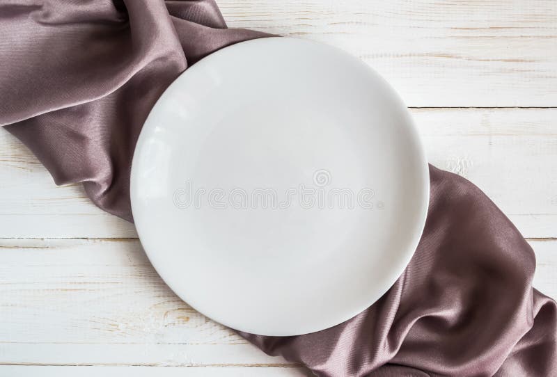 Piatto bianco sul tovagliolo lilla a quadretti del raso fotografia stock libera da diritti Piatto bianco sul tovagliolo lilla a quadretti del raso fotografia stock libera da diritti