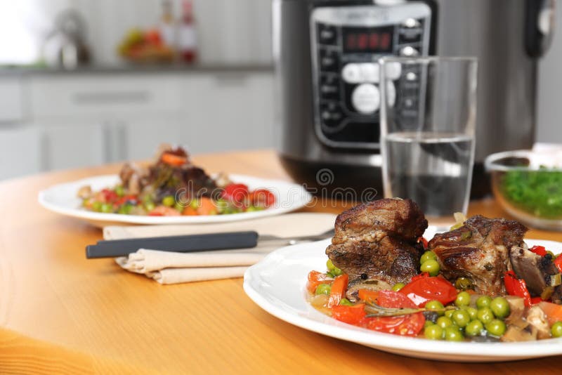 Piatto con carne e contorno pronto in multi fornello sulla tavola di legno in cucina Spazio per
