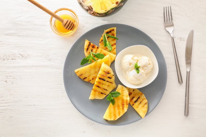 Piatto con le fette arrostite dell'ananas e gelato sulla tavola di legno fotografie stock Piatto con le fette arrostite dell'ananas e gelato sulla tavola di legno fotografie stock