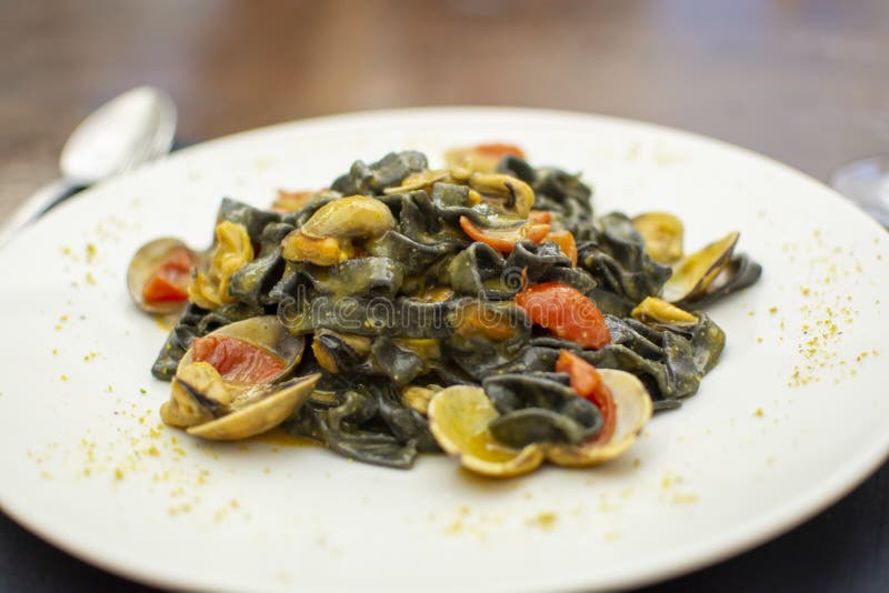 Piatto della pasta dei frutti di mare, fettuccini nero italiano con le vongole del vongole e cozze fotografie stock libere da diritti Piatto della pasta dei frutti di mare, fettuccini nero italiano con le vongole del vongole e cozze fotografie stock libere da diritti