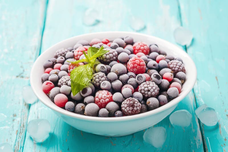Piatto delle bacche congelate fresche su un fondo del turchese immagine stock libera da diritti Piatto delle bacche congelate fresche su un fondo del turchese immagine stock libera da diritti