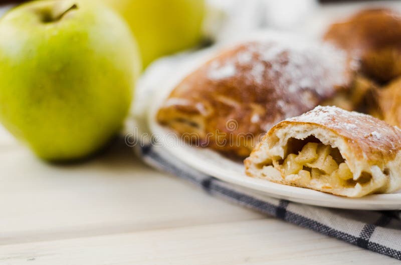 Piatto di recente al forno della torta di mele e due mele gialle fresche su fondo e sull'asciugamano di legno leggeri immagine stock Piatto di recente al forno della torta di mele e due mele gialle fresche su fondo e sull'asciugamano di legno leggeri immagine stock