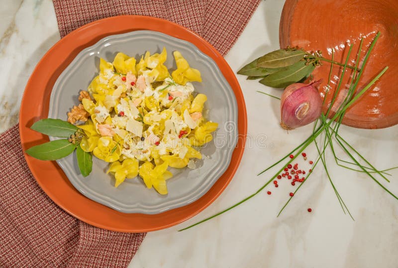 Piatto italiano dei tortellini fatti a mano con il pepe crema e rosa del salmone, Decorato con la foglia, la cipolla e la erba ci fotografie stock Piatto italiano dei tortellini fatti a mano con il pepe crema e rosa del salmone, Decorato con la foglia, la cipolla e la erba ci fotografie stock