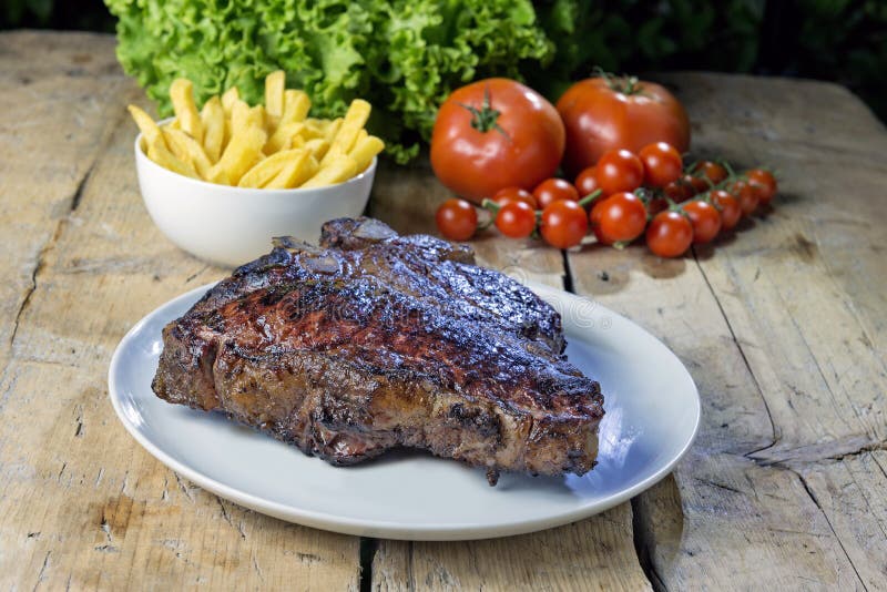 Piatto rotondo con la bistecca di manzo arrostita della lombata sulla tavola di legno fotografia stock libera da diritti Piatto rotondo con la bistecca di manzo arrostita della lombata sulla tavola di legno fotografia stock libera da diritti
