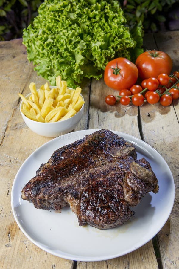Piatto rotondo con la bistecca di manzo arrostita della lombata sulla tavola di legno immagini stock Piatto rotondo con la bistecca di manzo arrostita della lombata sulla tavola di legno immagini stock