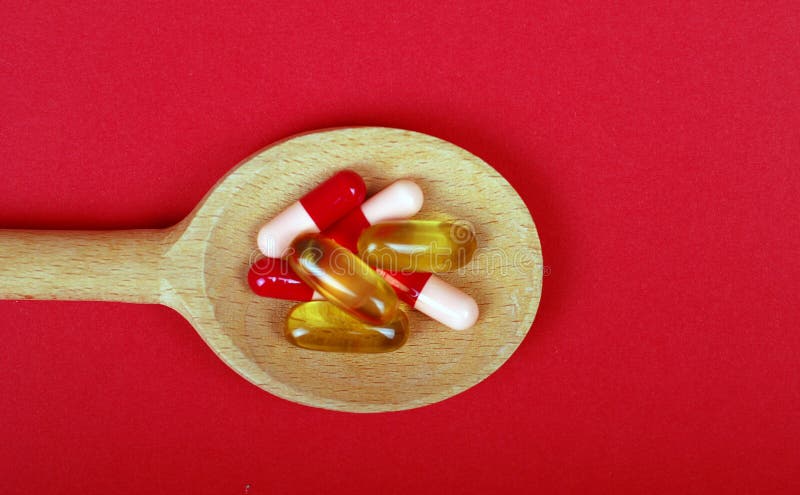 Omega 3 pill and capsules on wooden spoon