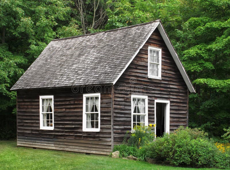 Small unpainted, natural dark wood rustic house, with trees and bushes. Small unpainted, natural dark wood rustic house, with trees and bushes.