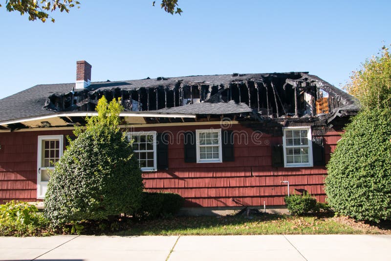 Piccola casa rossa con il tetto e l'ultimo piano distrutti da incendio fotografia stock Piccola casa rossa con il tetto e l'ultimo piano distrutti da incendio fotografia stock