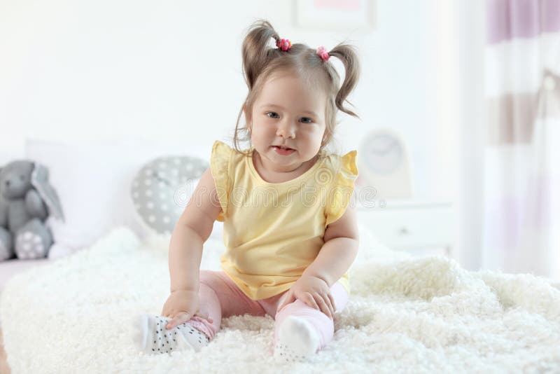 Piccola neonata adorabile che si siede sul letto immagine stock libera da diritti Piccola neonata adorabile che si siede sul letto immagine stock libera da diritti