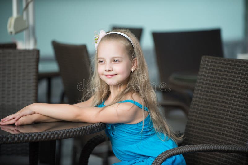 Piccola neonata sorridente in vestito blu vicino alla tavola del caffè fotografie stock libere da diritti Piccola neonata sorridente in vestito blu vicino alla tavola del caffè fotografie stock libere da diritti