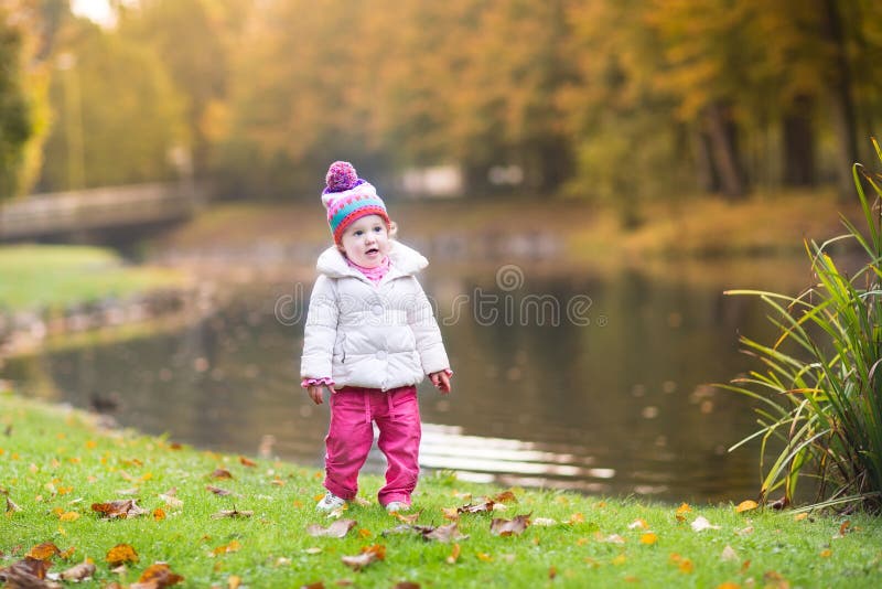 Piccola neonata sveglia accanto al fiume nel parco di autunno