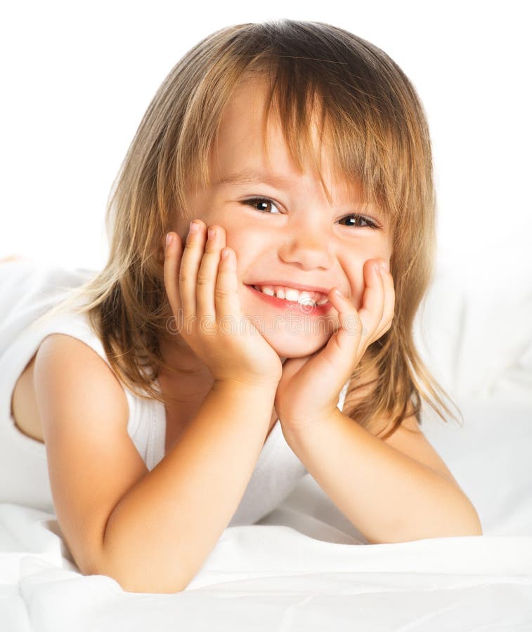 Piccola ragazza allegra sorridente felice in un letto isolato immagini stock libere da diritti Piccola ragazza allegra sorridente felice in un letto isolato immagini stock libere da diritti