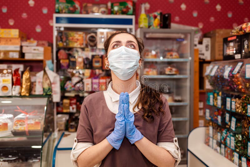 Piccole imprese durante la pandemia. una lavoratrice in maschera medica e guanti di gomma si spalanca le mani e guarda con aria al