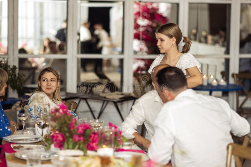 Piccoli discorsi tra donne e uomini di età diversa al tavolo delle feste. Una famiglia felice e i suoi amici chiacchierano a un fotografia stock libera da diritti