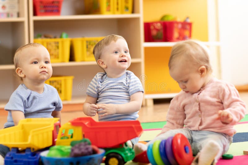Piccoli ragazzi e una ragazza che giocano insieme in una stanza d'asilo bambini in tendopoli in un centro di assistenza diurna