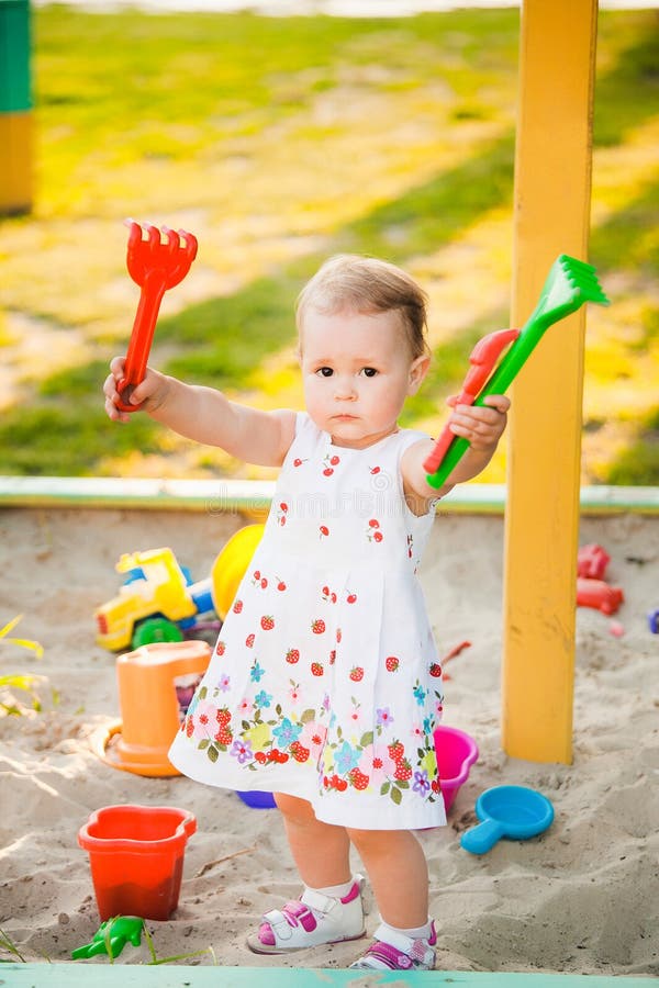 Piccolo bambino che gioca con i giocattoli in sabbia sul campo da giuoco dei bambini fotografia stock libera da diritti Piccolo bambino che gioca con i giocattoli in sabbia sul campo da giuoco dei bambini fotografia stock libera da diritti