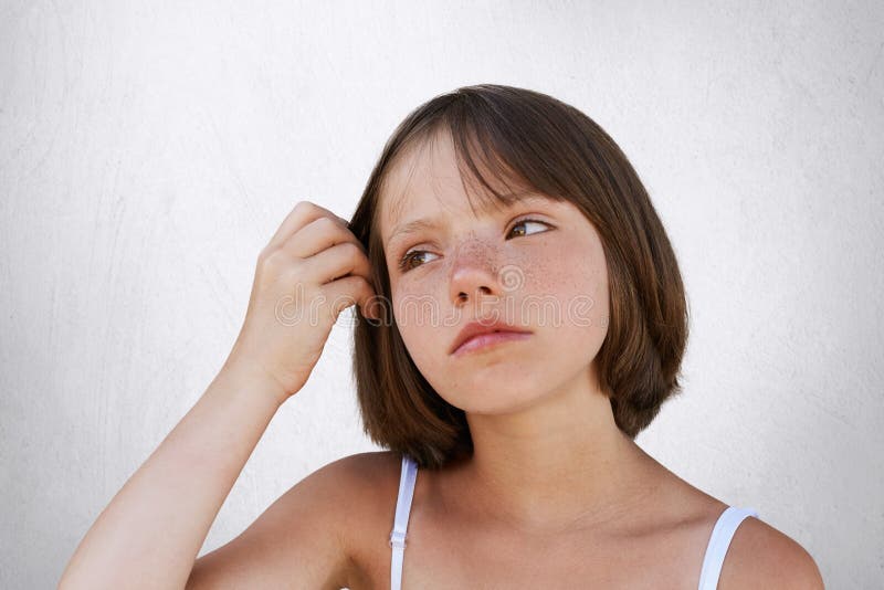 Piccolo bambino freckled serio, tenente la sua mano su capelli, espressione premurosa di havin, guardante da parte Bella ragazza fotografia stock libera da diritti Piccolo bambino freckled serio, tenente la sua mano su capelli, espressione premurosa di havin, guardante da parte Bella ragazza fotografia stock libera da diritti