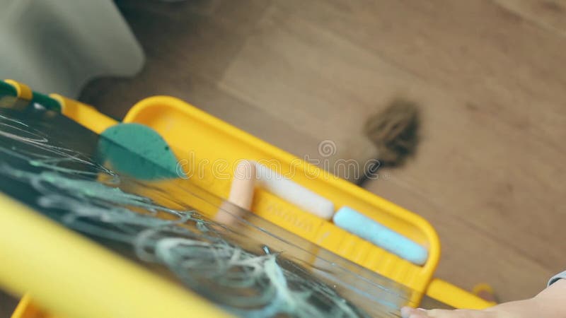 Piccolo bambino sveglio che impara disegnare con gesso su una lavagna