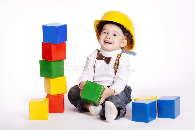 Piccolo ingegnere con i giochi del casco con i cubi fotografia stock libera da diritti Piccolo ingegnere con i giochi del casco con i cubi fotografia stock libera da diritti