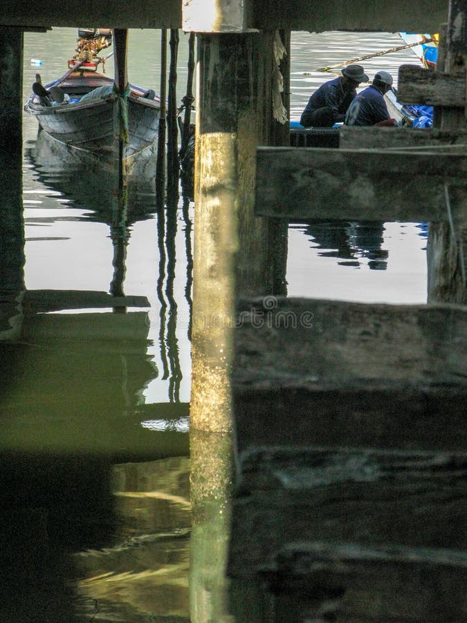 Piccolo peschereccio attraccato sotto il ponte sul mare fotografia stock libera da diritti Piccolo peschereccio attraccato sotto il ponte sul mare fotografia stock libera da diritti