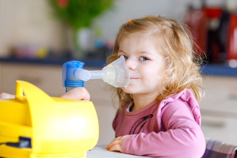Piccolo ragazza del bambino che fa inalazione con il nebulizzatore a casa Padre o madre che aiuta e che tiene il dispositivo Bamb immagini stock Piccolo ragazza del bambino che fa inalazione con il nebulizzatore a casa Padre o madre che aiuta e che tiene il dispositivo Bamb immagini stock