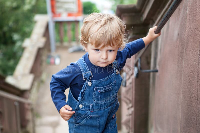 Piccolo ragazzo del bambino che scala le grandi scale in città immagini stock libere da diritti Piccolo ragazzo del bambino che scala le grandi scale in città immagini stock libere da diritti